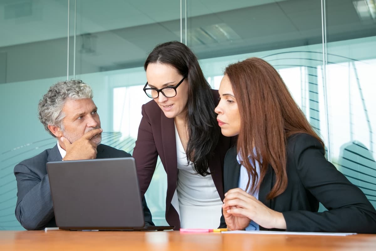 Three colleagues reviewing tax documents together at a laptop